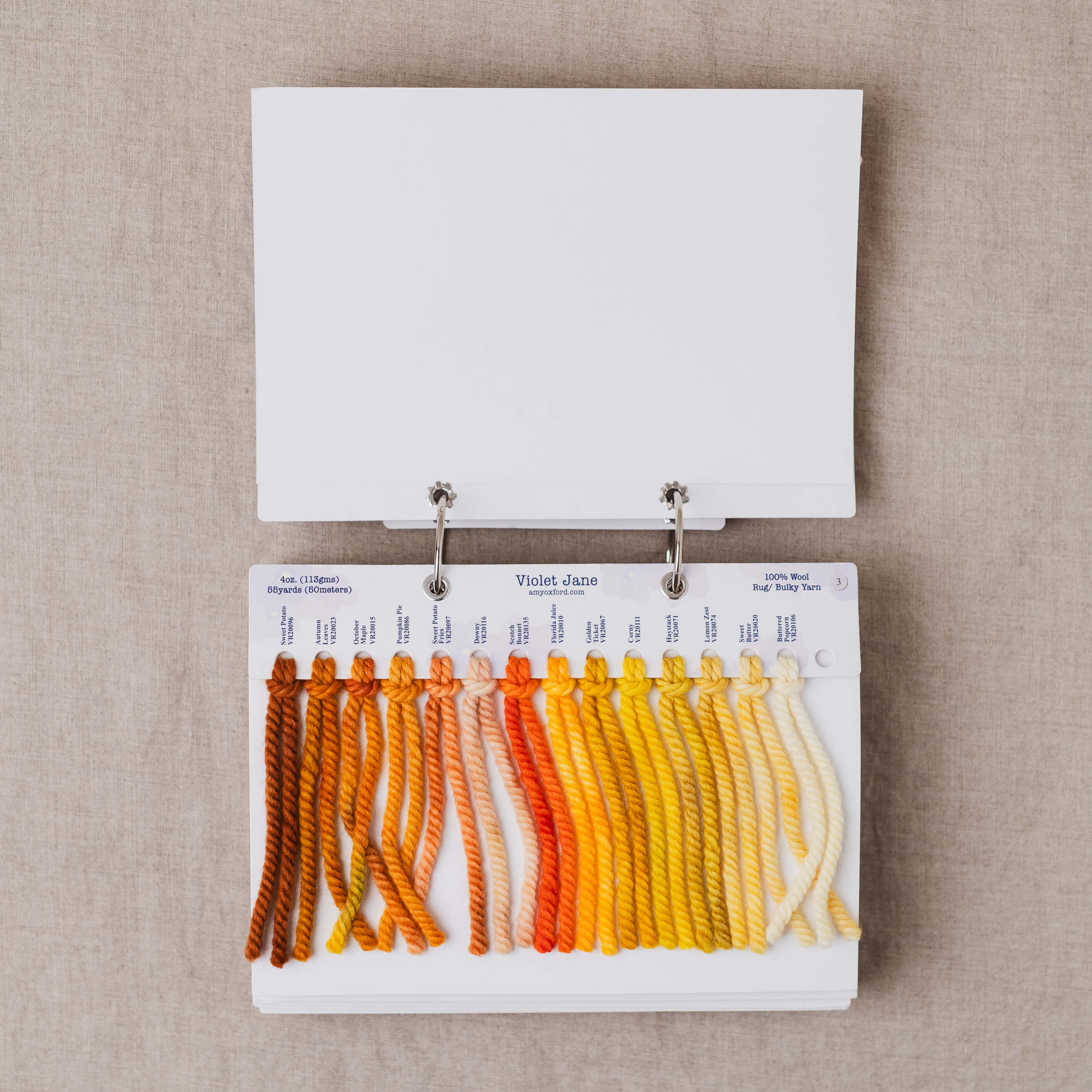 Yarn color swatch book with orange and yellow shades on a beige background