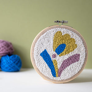 Abstract floral punch needle hoop with yarn stacked in the background