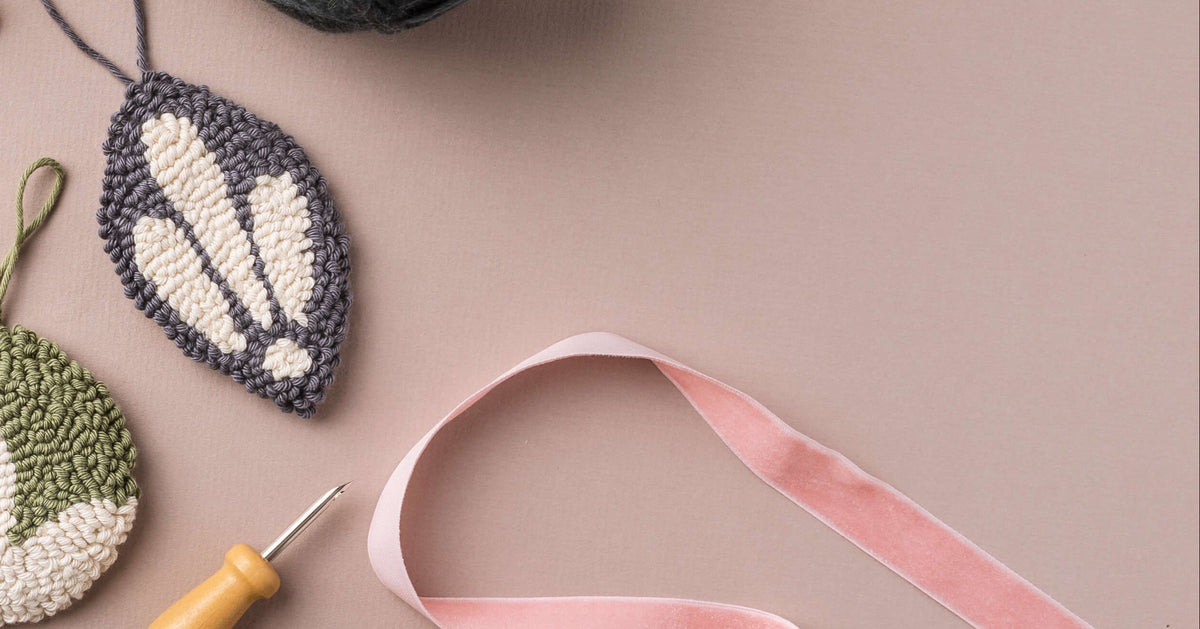 punch needle baubles on dusky pink background with ribbon and punch needle