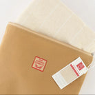 A tan canvas zippered pouch with a red square 'The Onion Company' logo patch, shown partially open with a folded cream woven textile inside. A product tag hangs from the zipper on a clean white background.