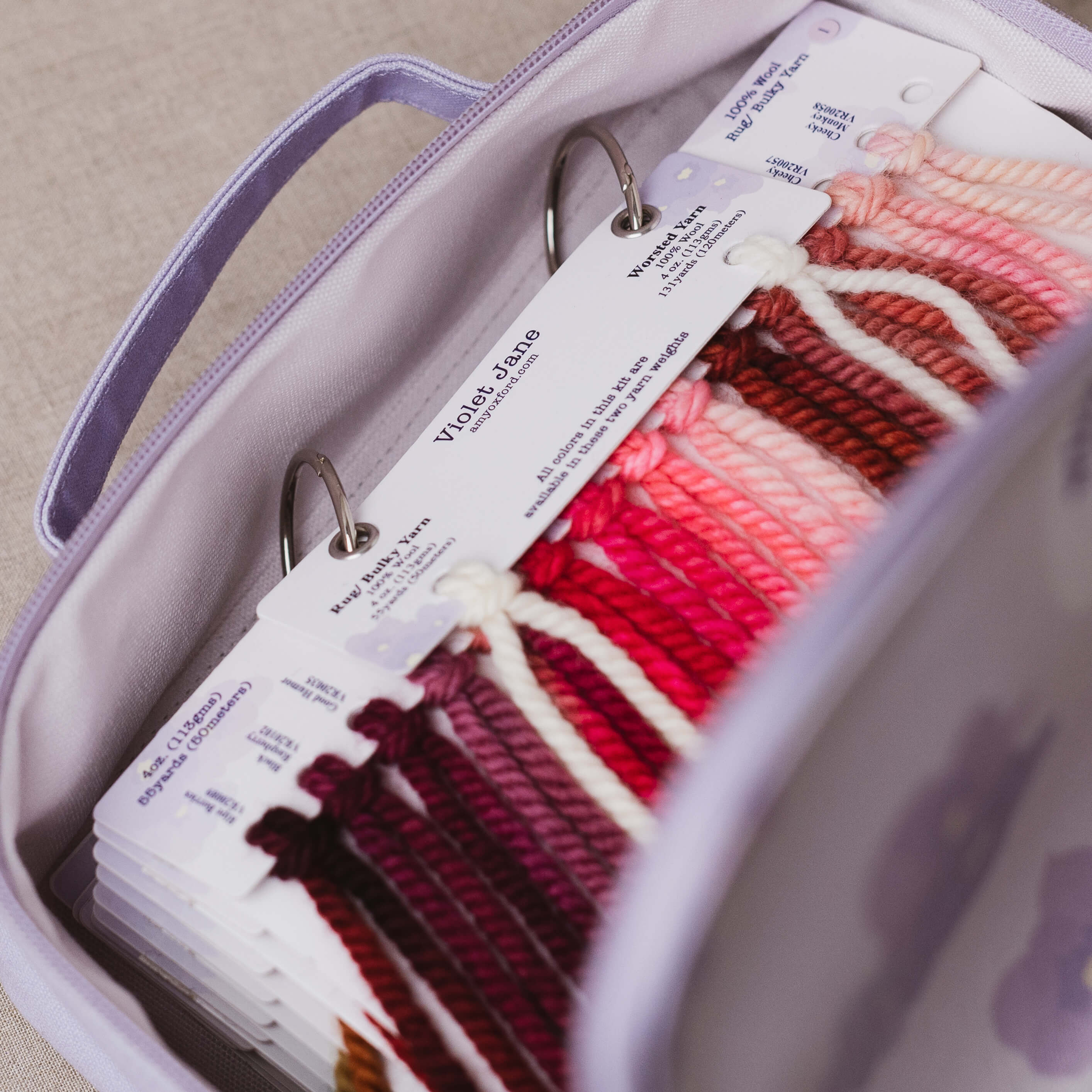Yarn with labels in a case, featuring a mix of red, pink, and white yarns.