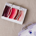 Color swatch card with yarn samples and a Violet Jane jar on a beige background