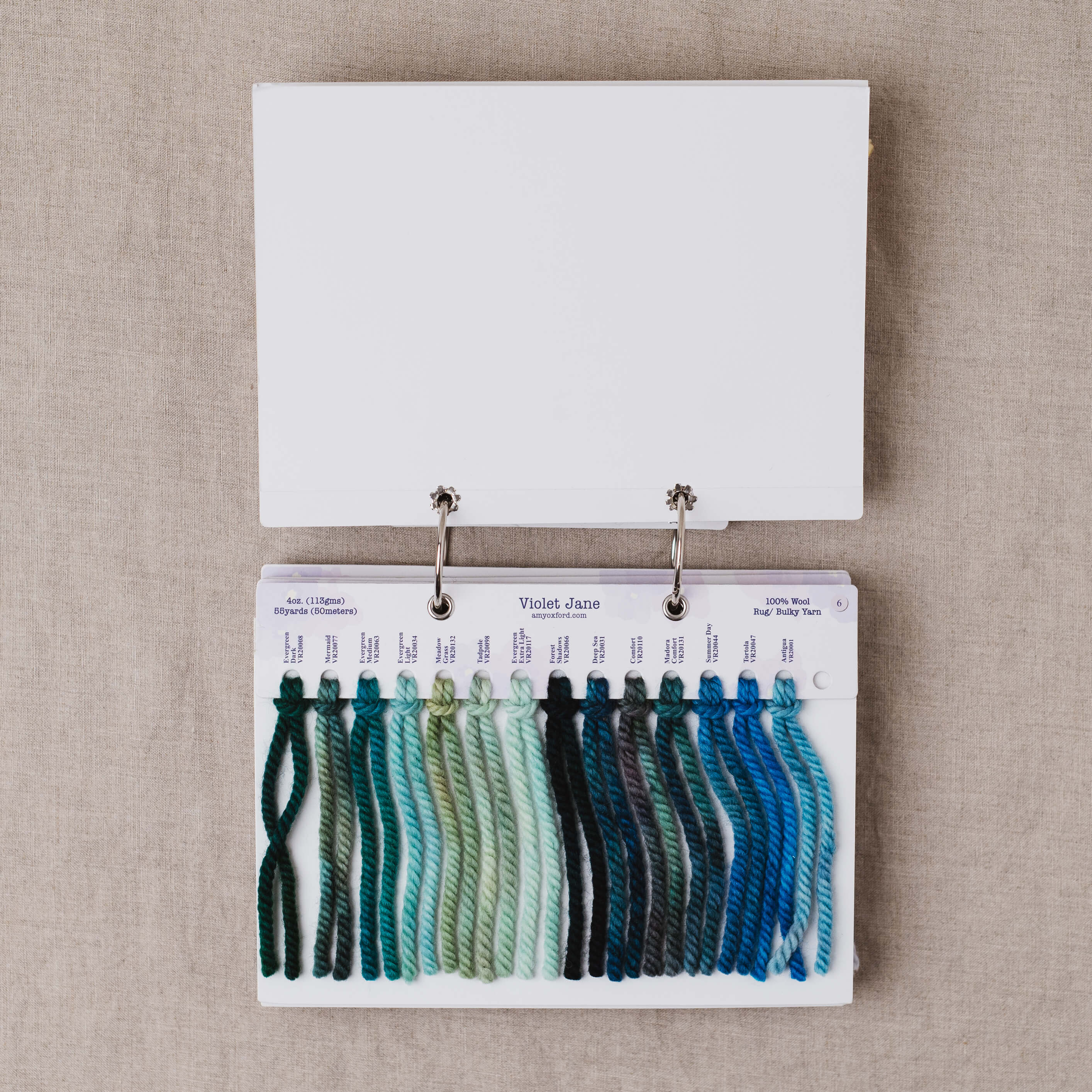 Yarn sample card with teal and green yarn swatches on a beige background