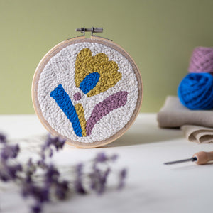 Punch needle hoop in abstract floral design with objects blurred in background