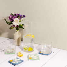 Load image into Gallery viewer, Punch needle coaster in blue and mint green, lemon water in a jug with glasses atop the coasters. A slice of lemon lies in the foreground.