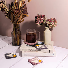 Load image into Gallery viewer, Lilac and dark grey floral punch needle coasters with books, vase and mug of tea propped on a coaster.