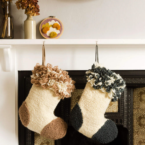 Punch needle stockings hanging from a fireplace