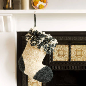 Punch needle stocking hanging from a fireplace