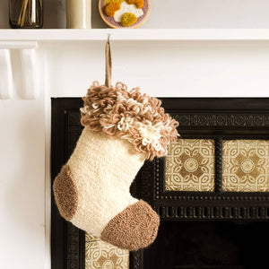 Punch needle stocking hanging from a fireplace