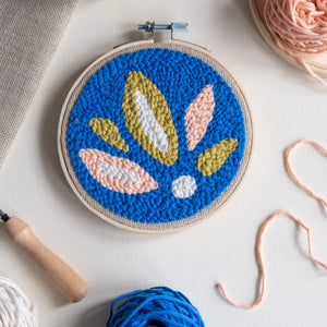 Summer leaves punch needle hoop laid flat with fabric, yarn and punch needle coming into shot