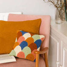 Load image into Gallery viewer, Scallop punch needle cushion propped on light pink chair with tan cushion and book open