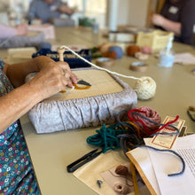 Load image into Gallery viewer, Student working on a gripper frame at an Oxford punch needle workshop