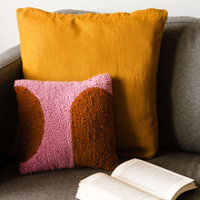 Load image into Gallery viewer, Pink and orange cushion propped on sofa with open book
