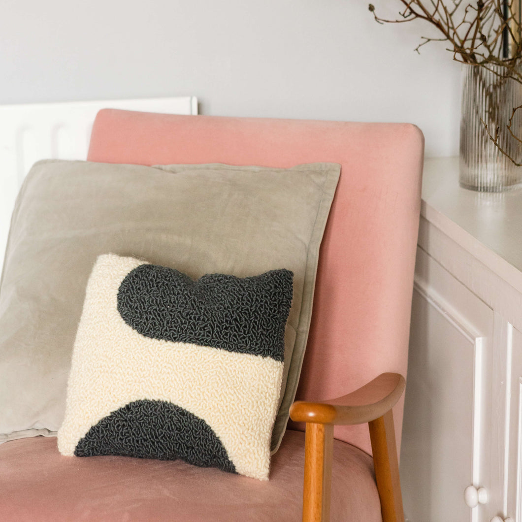 Grey and white shapes cushion propped on pink chair with light grey cushion